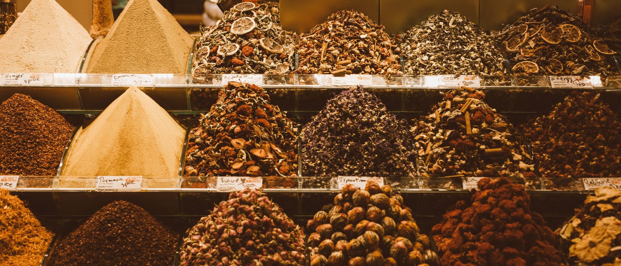 Heaps of whole and ground spices displayed side by side in a market shop.