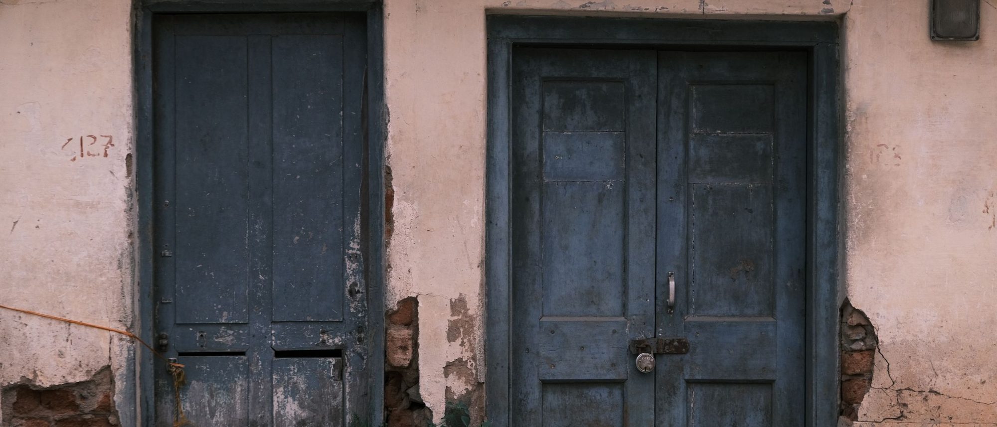 Weathered blue doors set into an old rustic wall in Bengaluru.