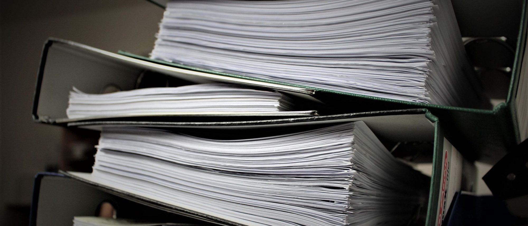 A close view of stacked binders thick with documents.
