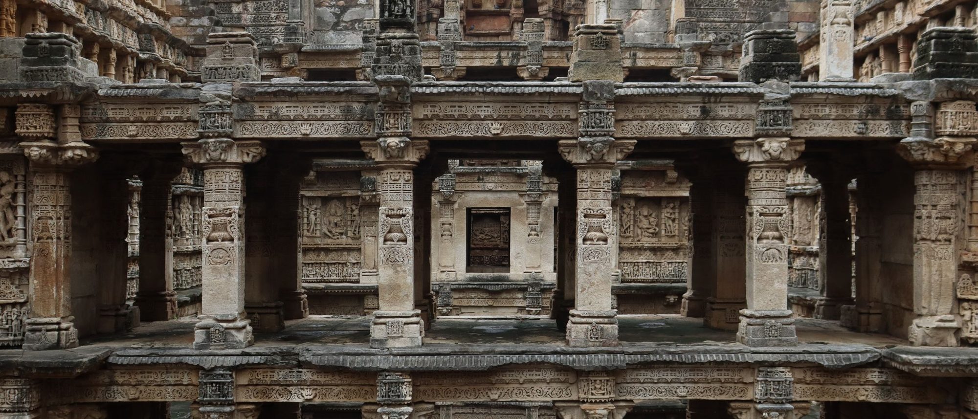 Carved stone terraces of an ancient stepwell descend level by level towards the water.