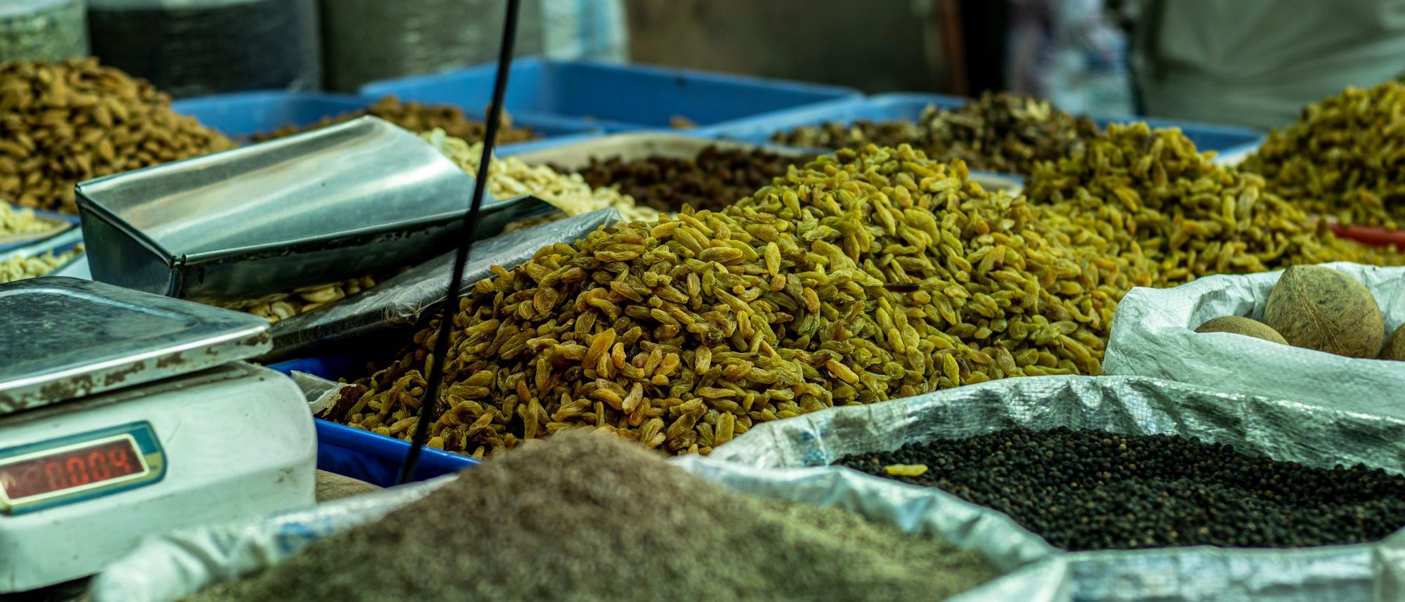 Open sacks of grains and spices stand in rows at a market stall in Delhi.