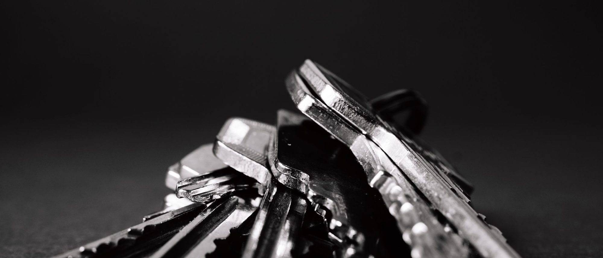 A pile of metal keys on a dark surface.