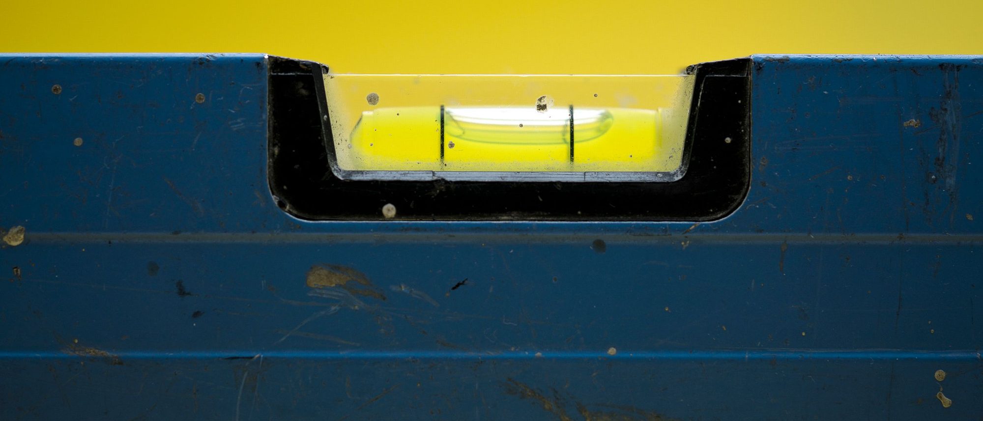 The bubble of a blue spirit level against a yellow ground