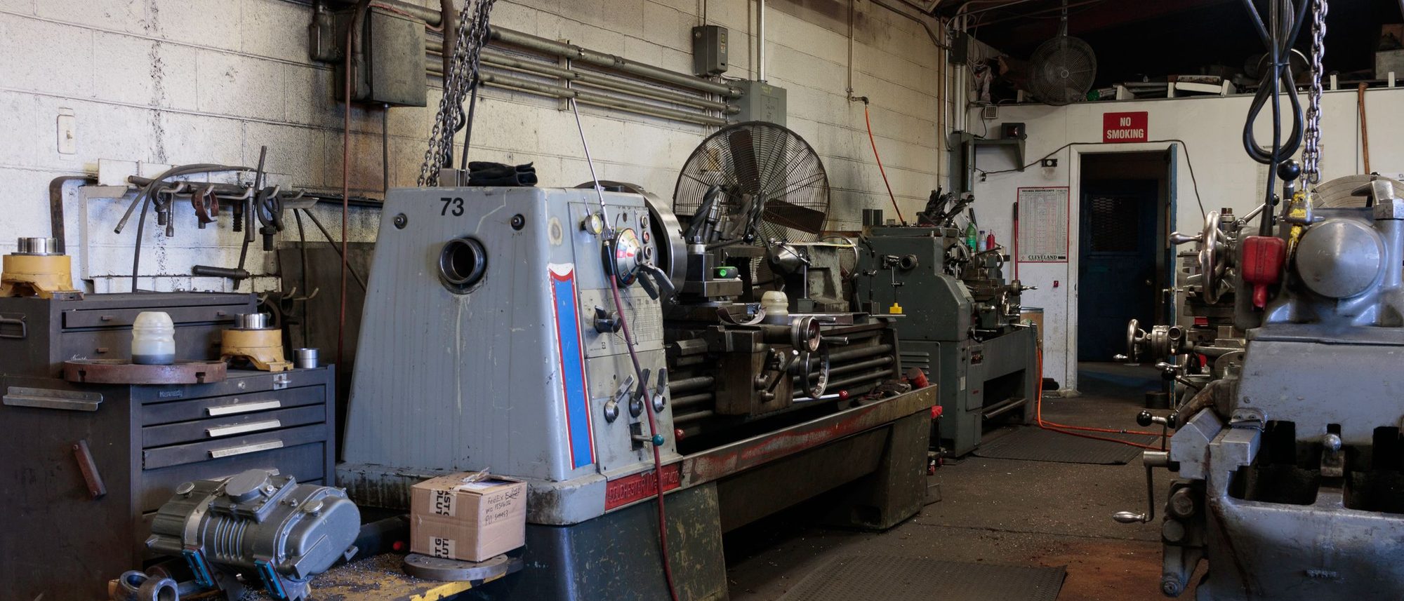 The interior of a metalworking machine shop with lathes and tools arranged along the floor.