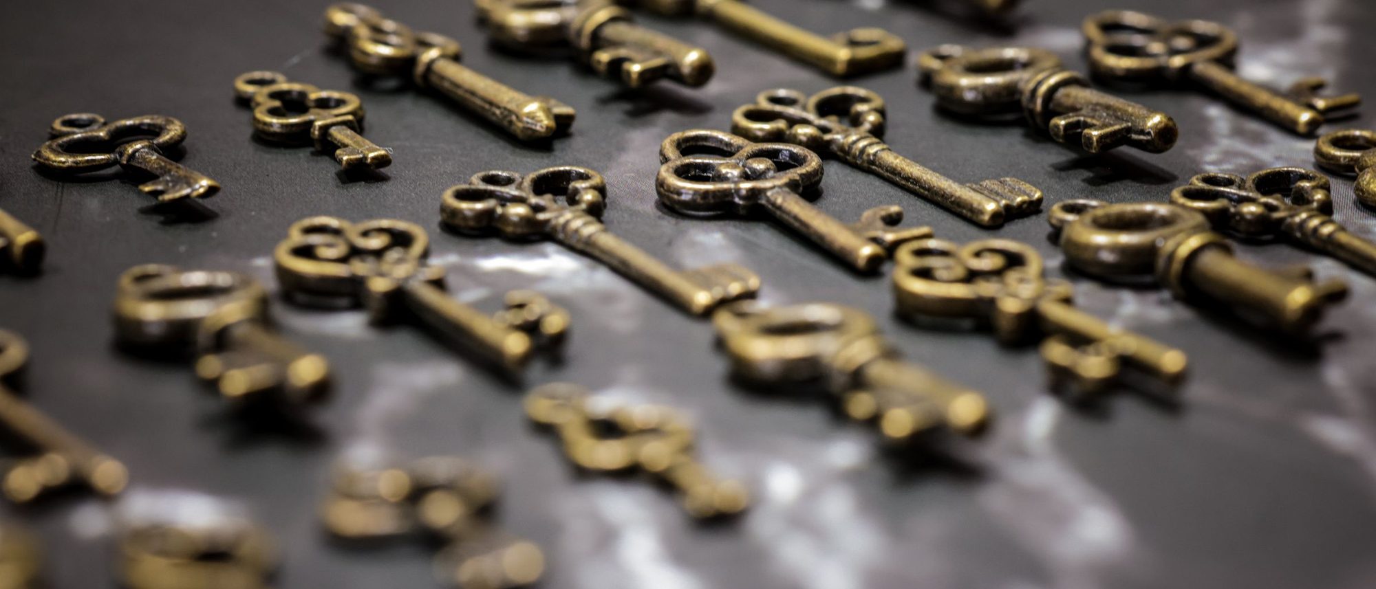 Vintage brass keys scattered across a dark surface.