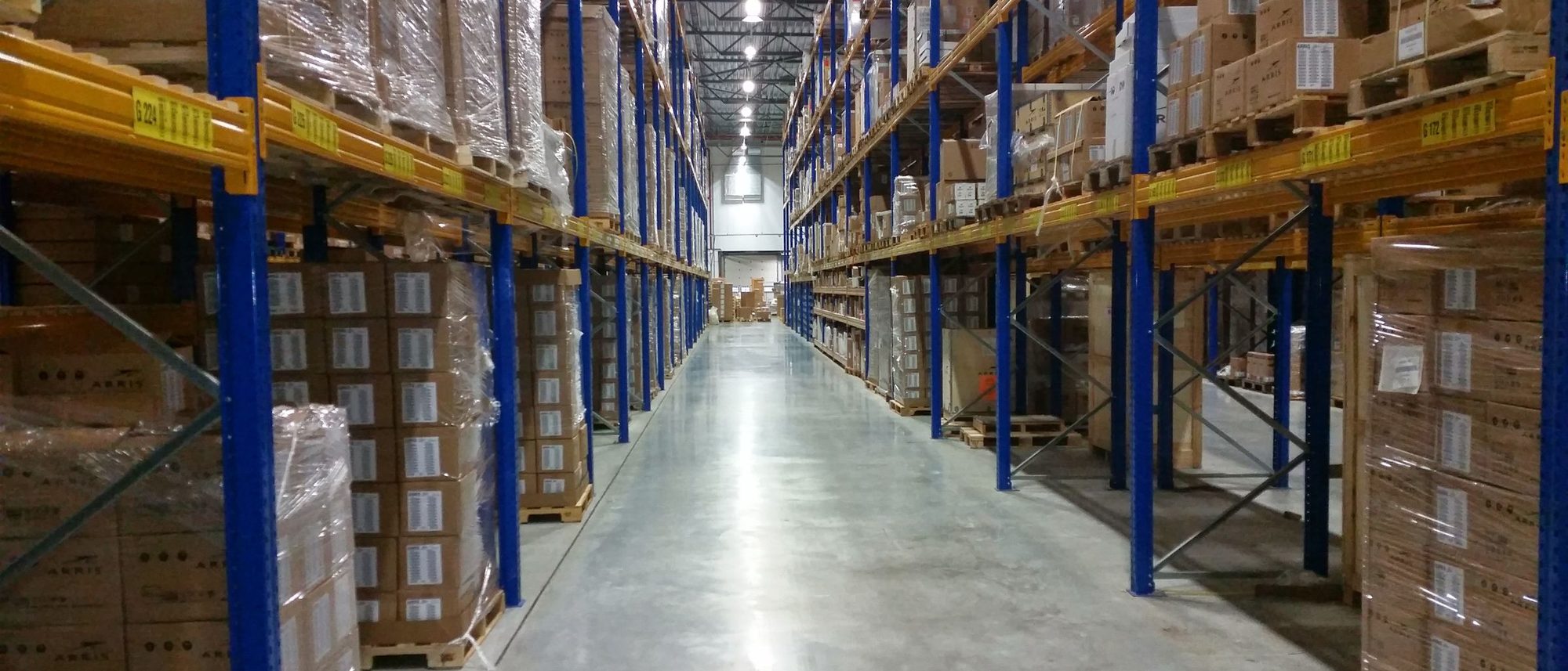A long warehouse aisle lined with stacks of cardboard boxes.