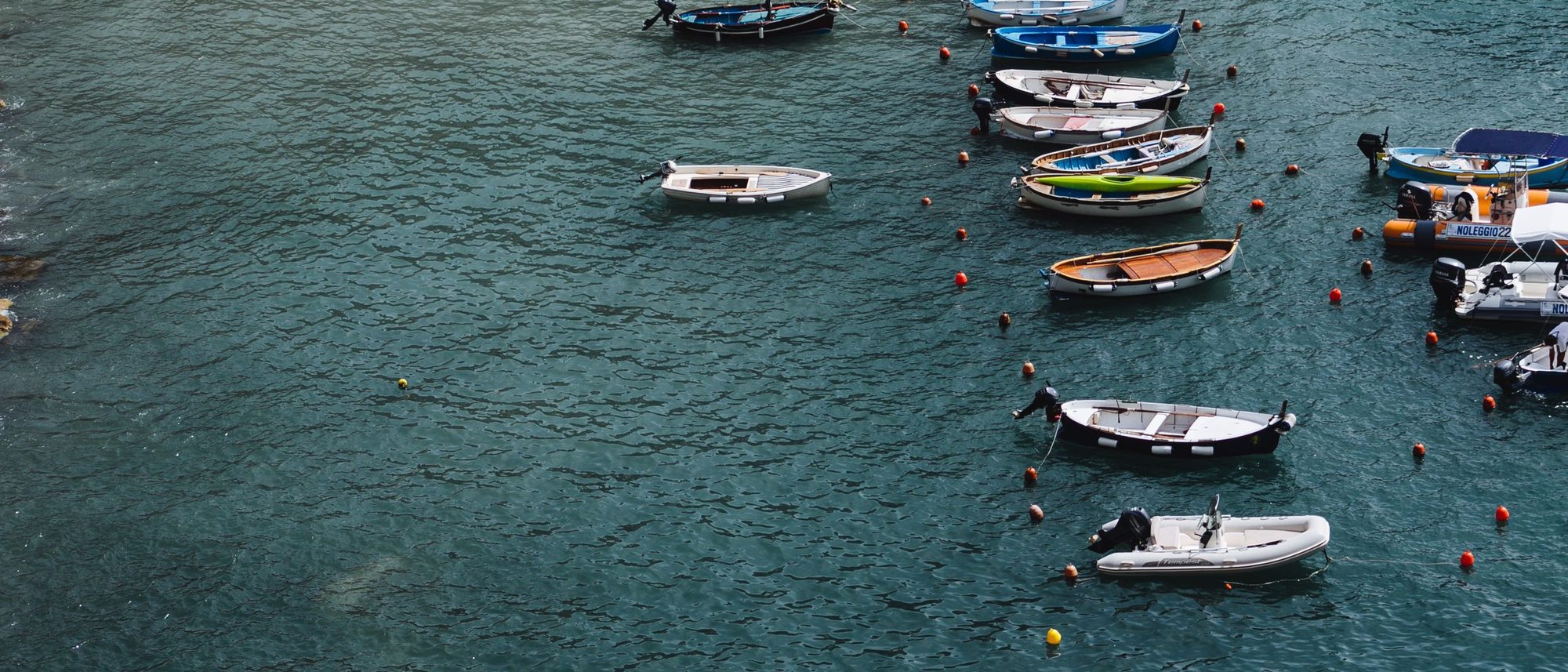 Boats of many sizes anchored in a calm harbour seen from above.