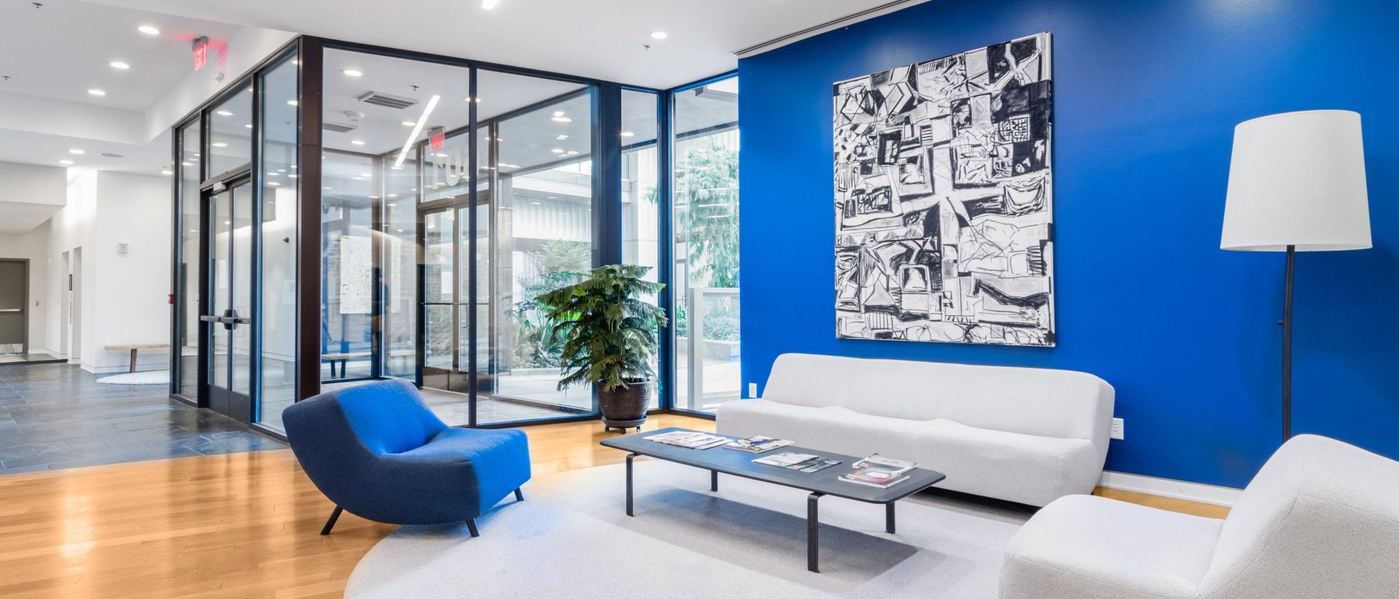An empty office waiting area with modern chairs beside a blue accent wall.