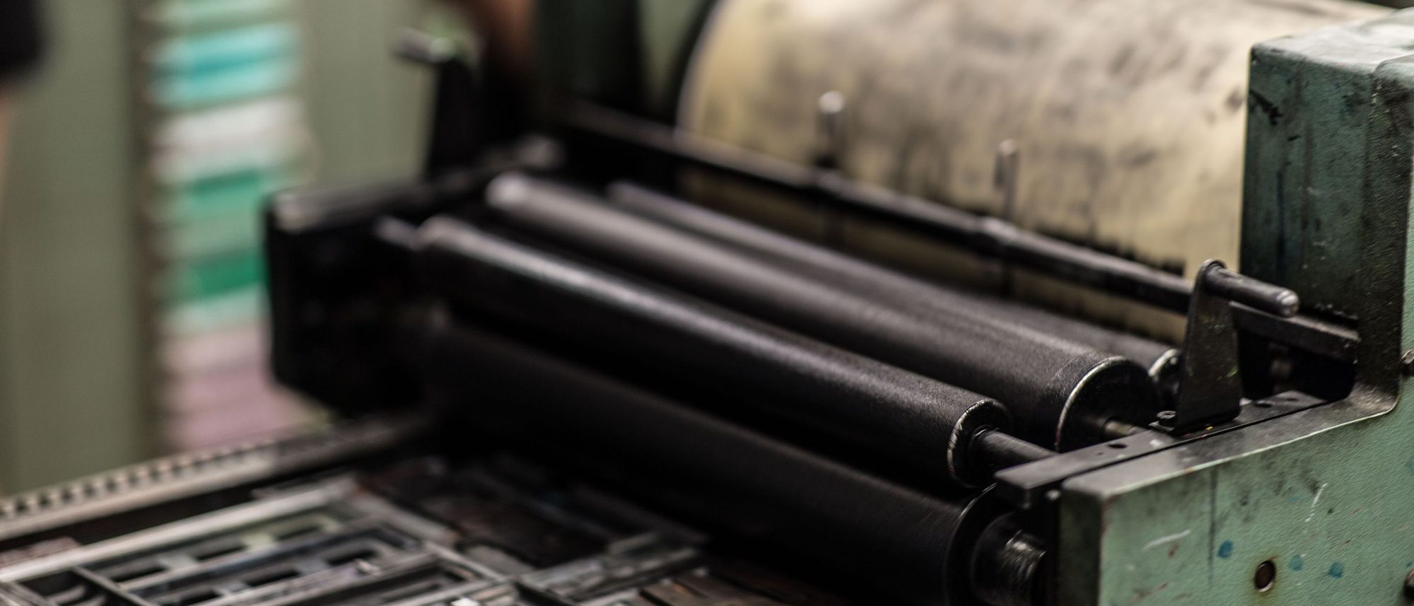 Close view of the rollers and gears of an industrial printing press.