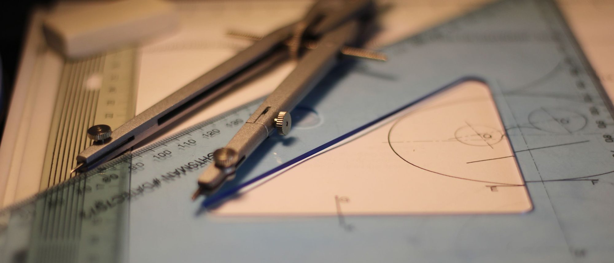 A compass and a set square resting on a sketchpad.
