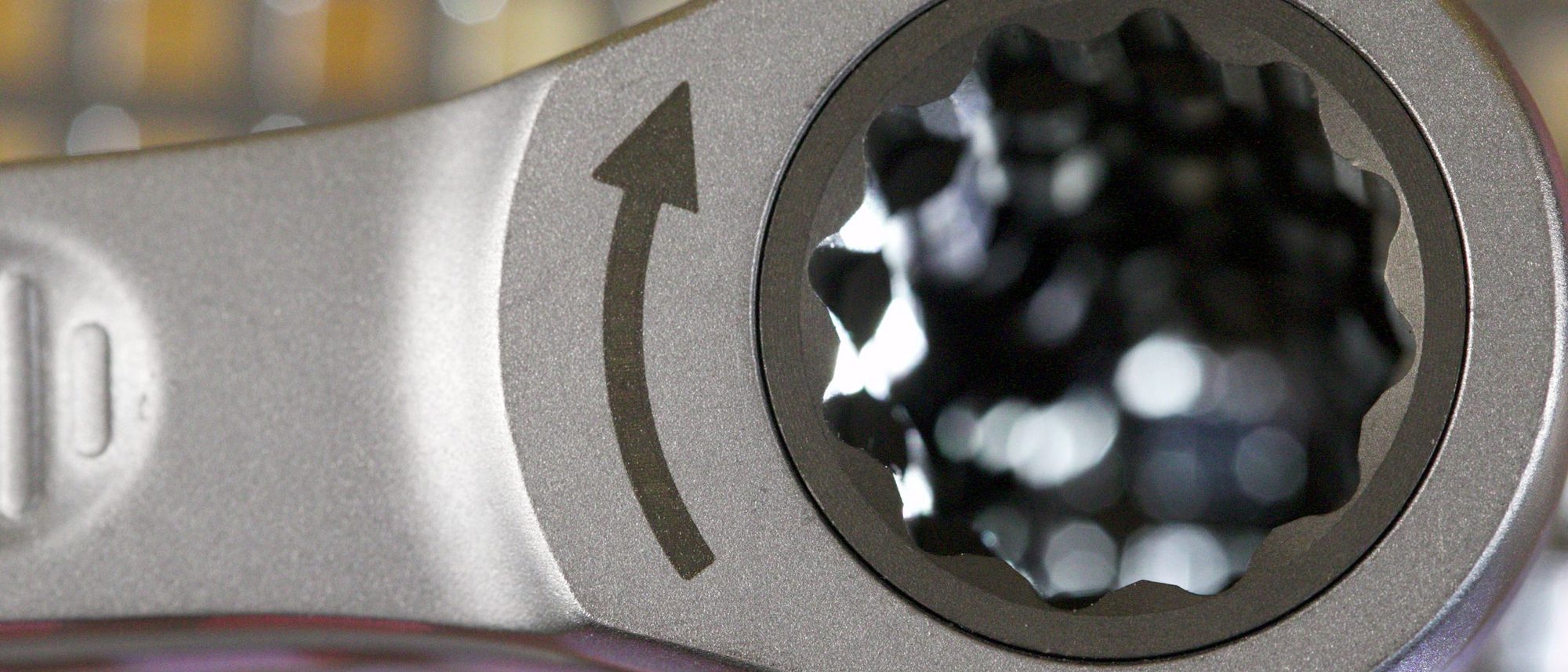 The polished head of a metal wrench in close-up.