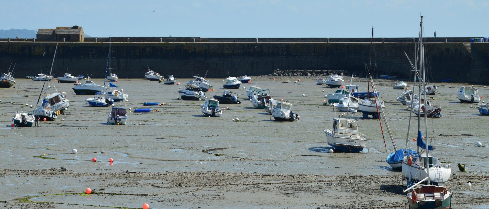 Fishing boats resting on the mudflats of Granville harbour at low tide.