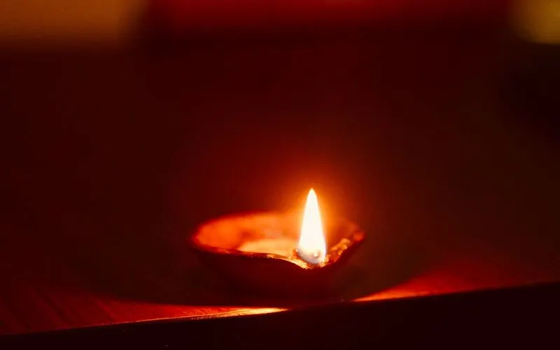 A single oil lamp burning on a wooden surface in the dark.