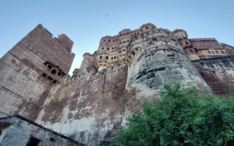 The sandstone walls and bastions of Mehrangarh Fort in Jodhpur seen from below against a blue sky