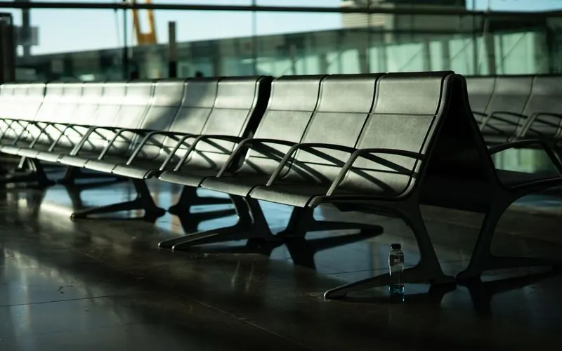 Empty metal benches in an airport terminal with low sun through the glass