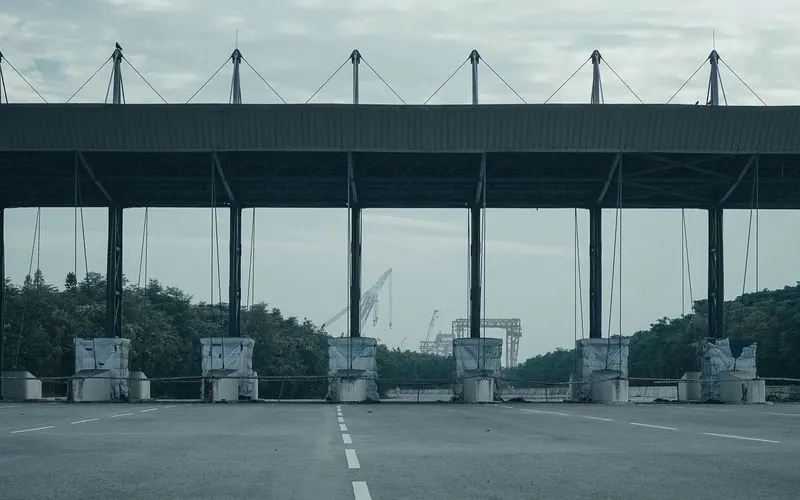 An empty toll gate on a deserted highway under an overcast sky