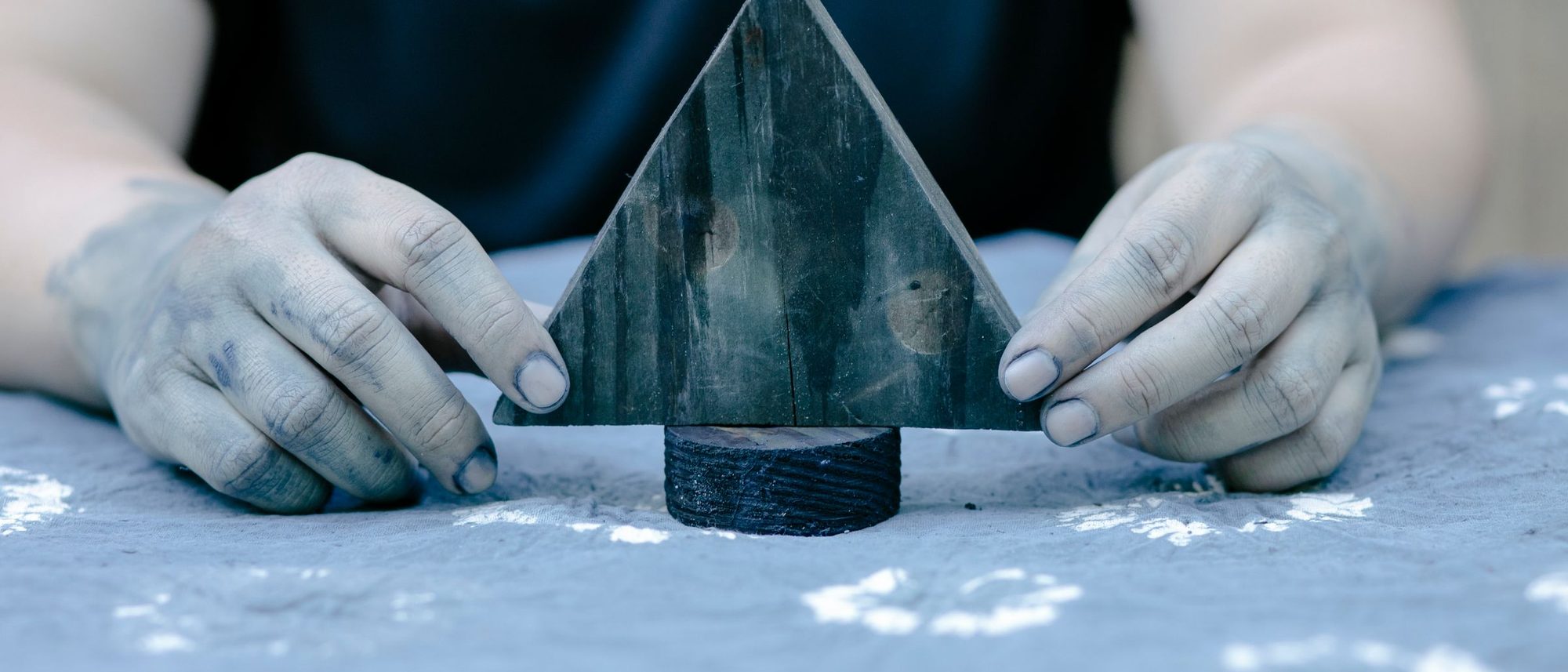 Hands press a carved wooden stamp onto fabric to print a pattern.